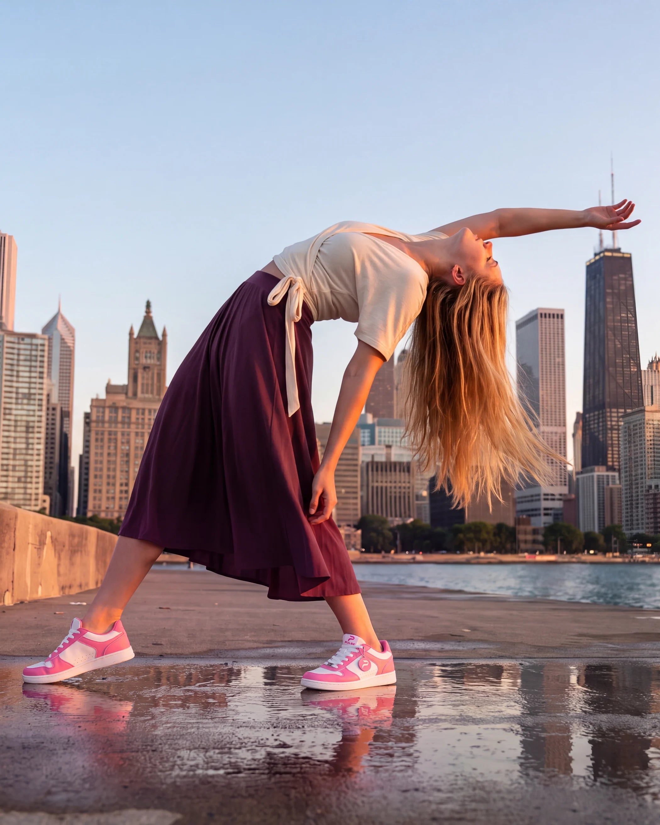 Dancer in a long skirt arching back on a waterfront, wearing Flow 2 Rouge dance sneakers