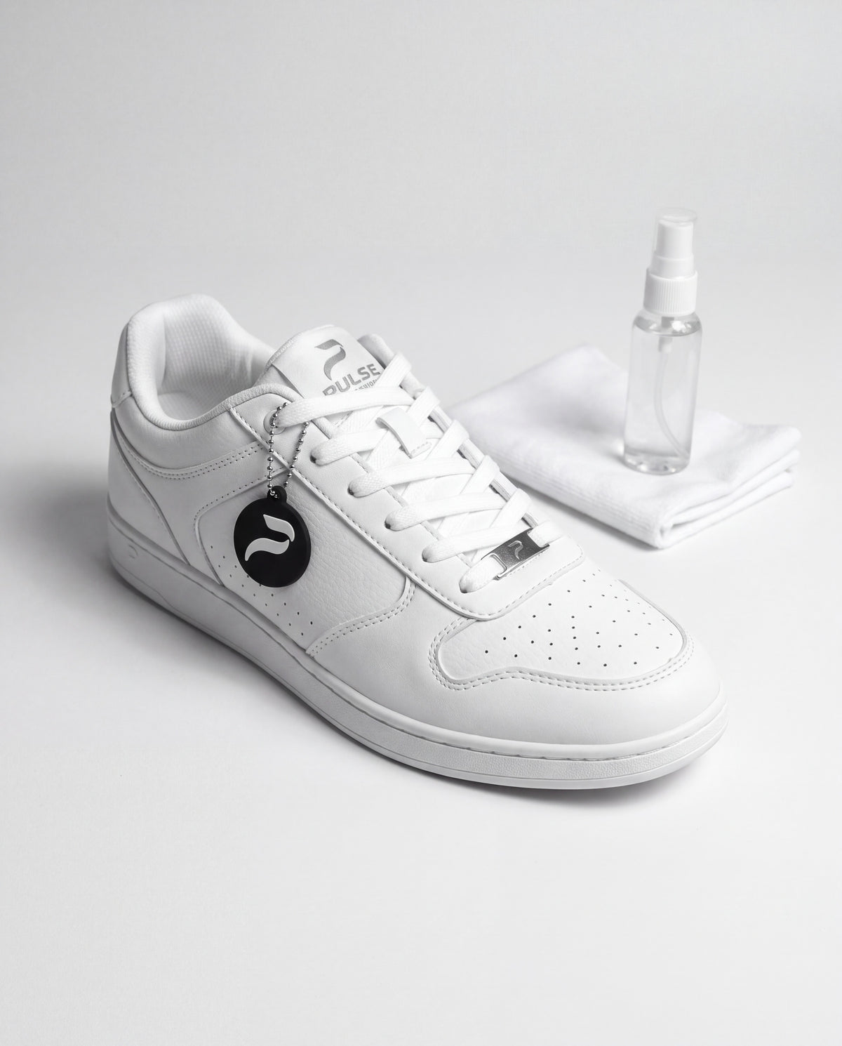 White Pulse Dance Shoes low-top dance sneaker with microfiber cloth and clear spray bottle on a pale gray studio surface