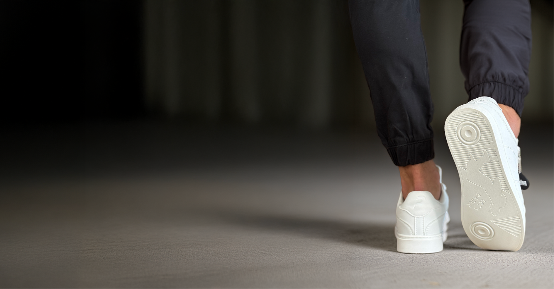 White sneakers being worn on a dark background